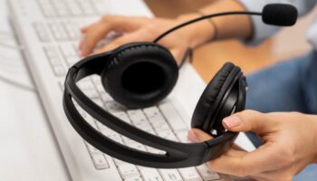 woman-working-call-center-holding-pair-headphones-scaled